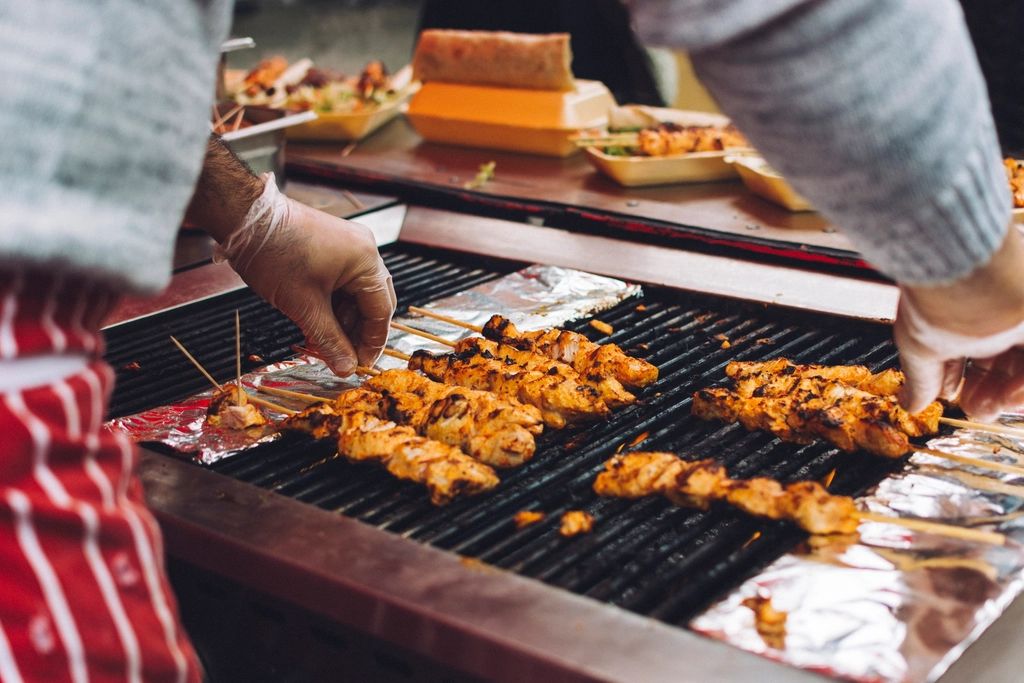 Peniaga membakar sate ayam dengan sarung tangan